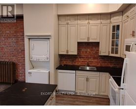 A kitchen with white appliances and a brick wall.