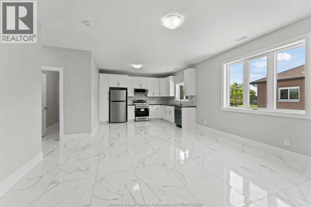 A spacious kitchen with white marble flooring and modern appliances.