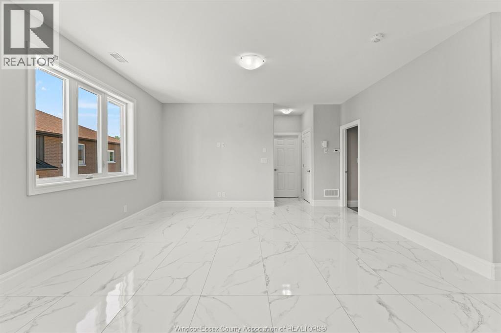 A spacious, empty room with marble flooring and a large window.