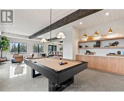 A pool table is in the middle of a room with a wood ceiling and a white wall.