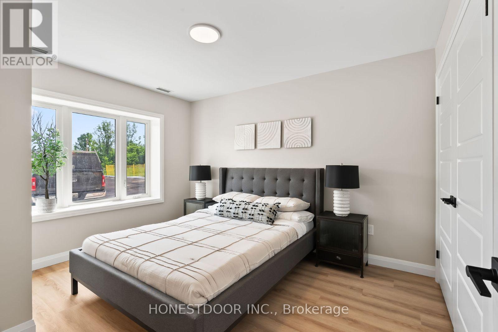 A bedroom with a bed, nightstand, and window.