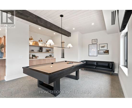 A pool table is in the middle of a room with a black couch and a shelf with decorative items.