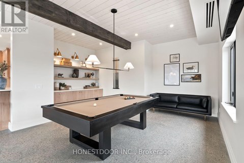 A pool table is in the middle of a room with a black couch and a shelf with decorative items.
