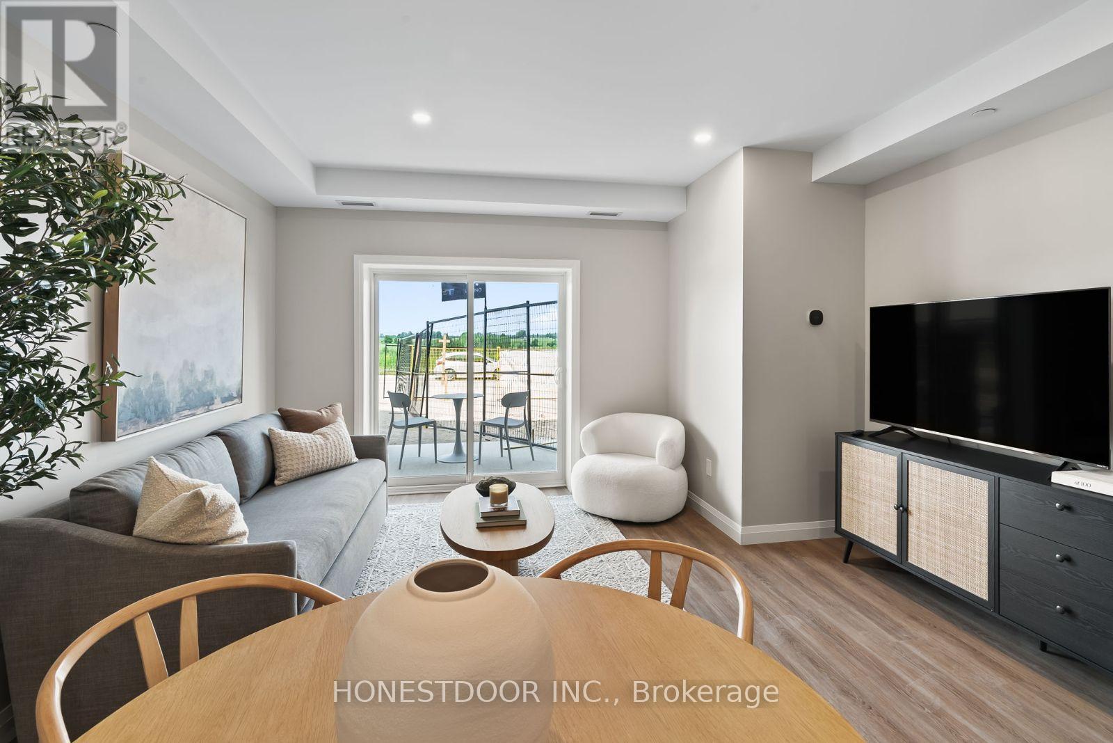 A modern living room with a wooden table and chairs, a grey sofa, and a television.