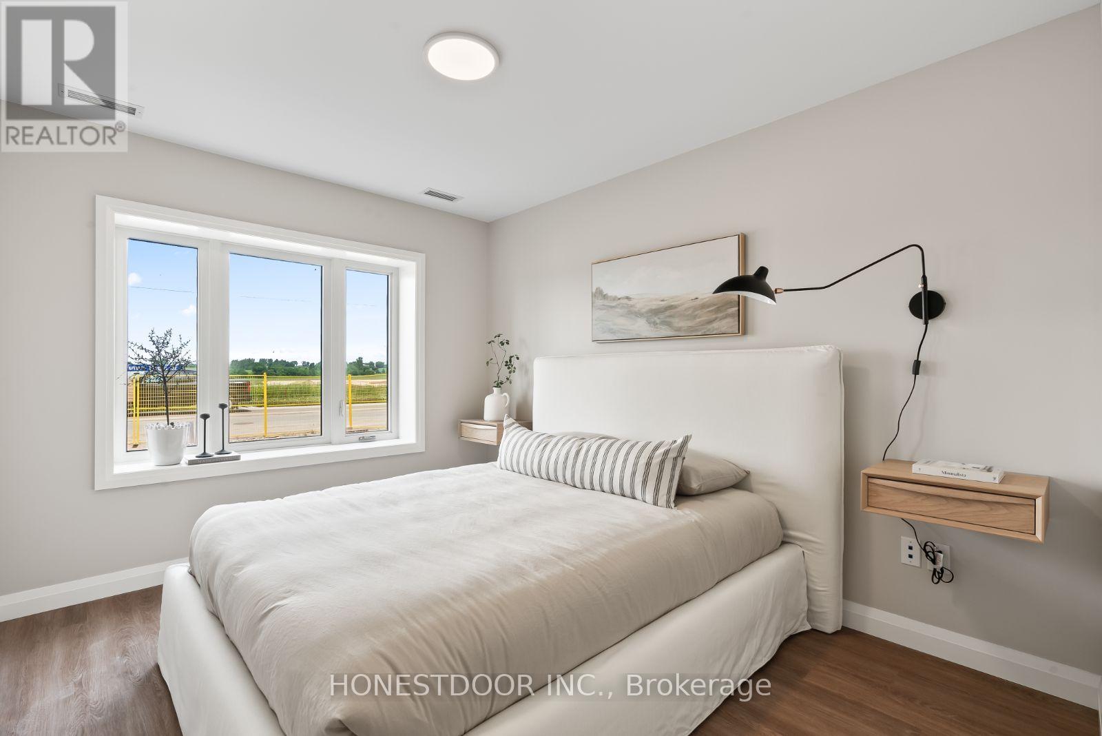 A bedroom with a large bed and a window overlooking a yellow fence.