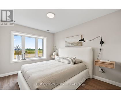 A bedroom with a large bed and a window overlooking a yellow fence.