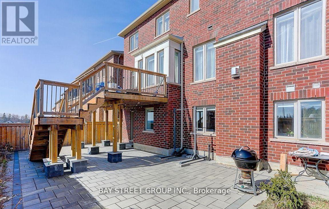 A red brick house with a wooden deck and a BBQ grill.