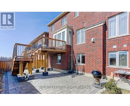 A red brick house with a wooden deck and a BBQ grill.