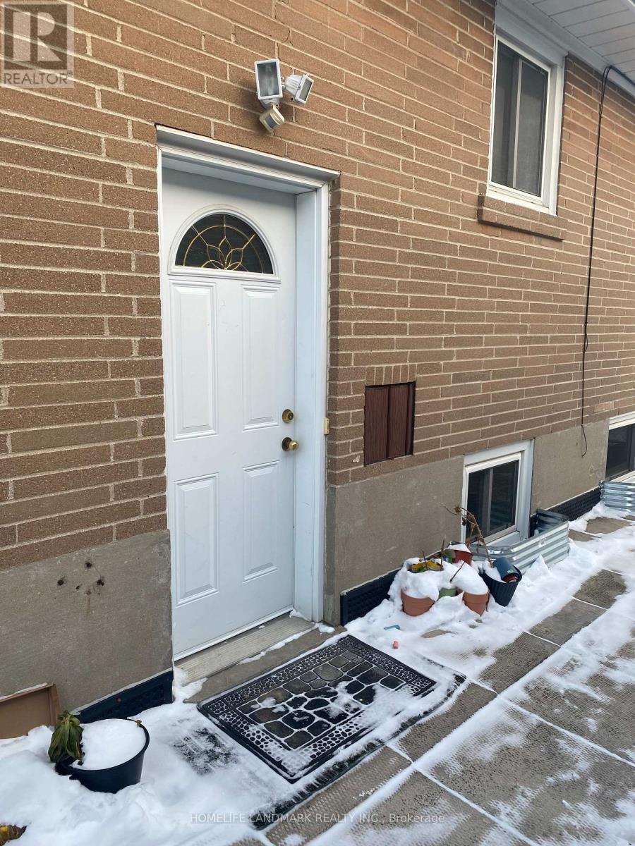 A white door is on the left side of a brick building.