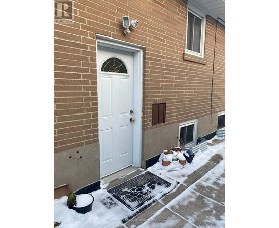 A white door is on the left side of a brick building.