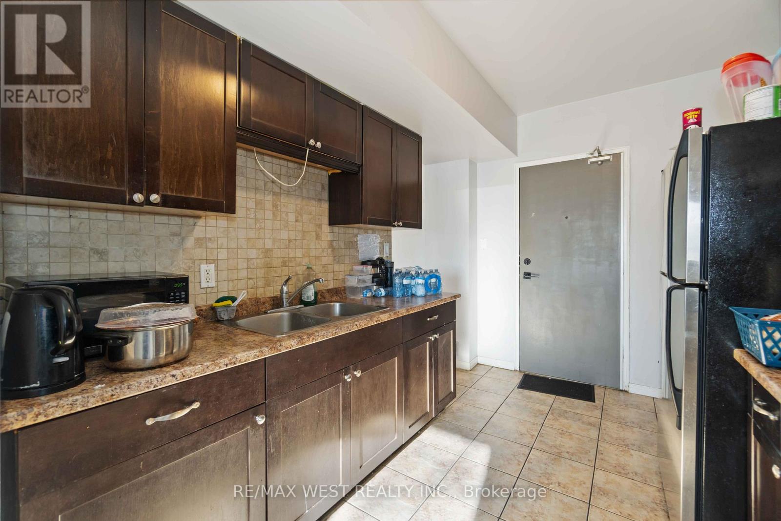 A kitchen with brown cabinets and a black refrigerator.