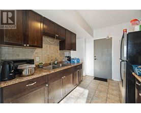 A kitchen with brown cabinets and a black refrigerator.