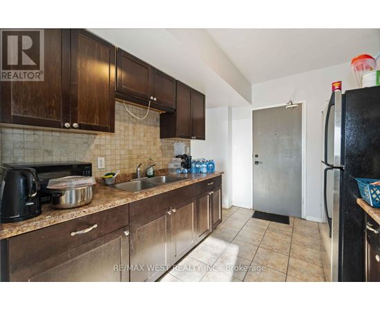 A kitchen with brown cabinets and a black refrigerator.