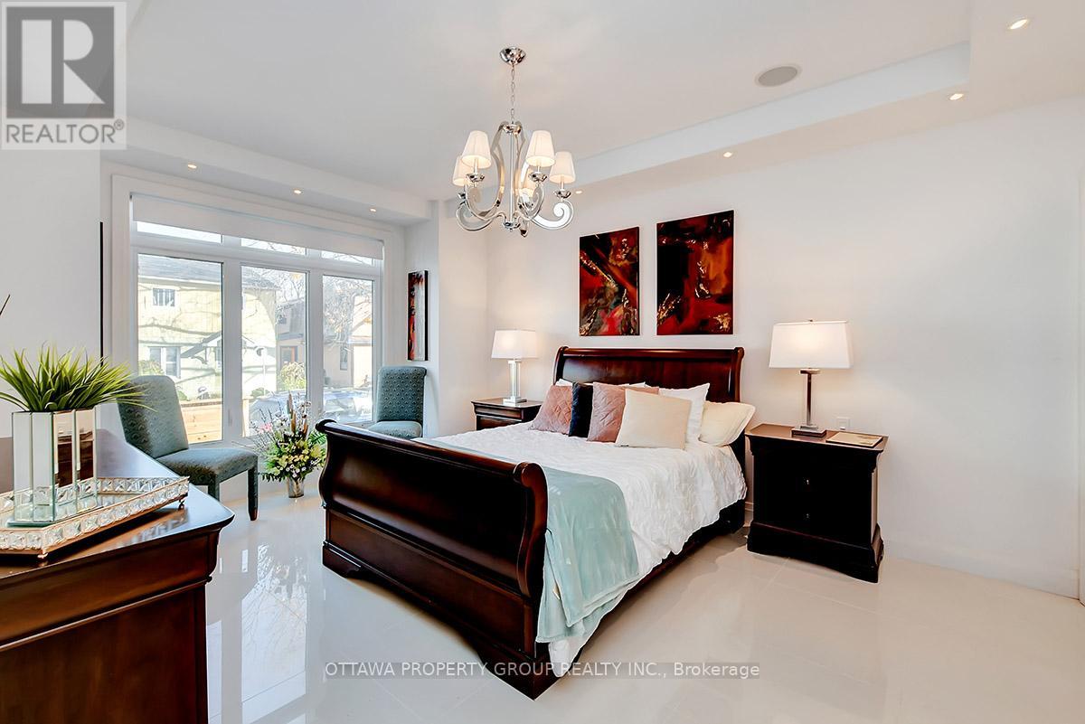 A bedroom with a large bed, a chair, and a chandelier.