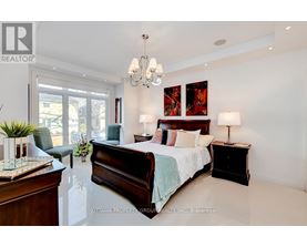 A bedroom with a large bed, a chair, and a chandelier.