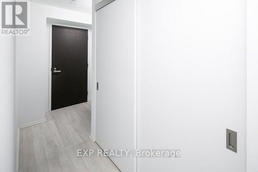 A black door is in a white hallway.