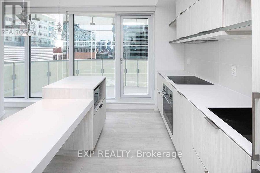 A modern kitchen with white cabinets and a glass door leading to a balcony.