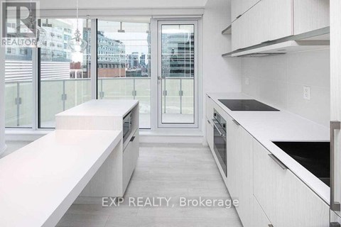 A modern kitchen with white cabinets and a glass door leading to a balcony.