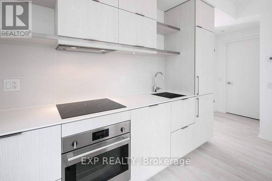 A white kitchen with a stove top oven and a sink.