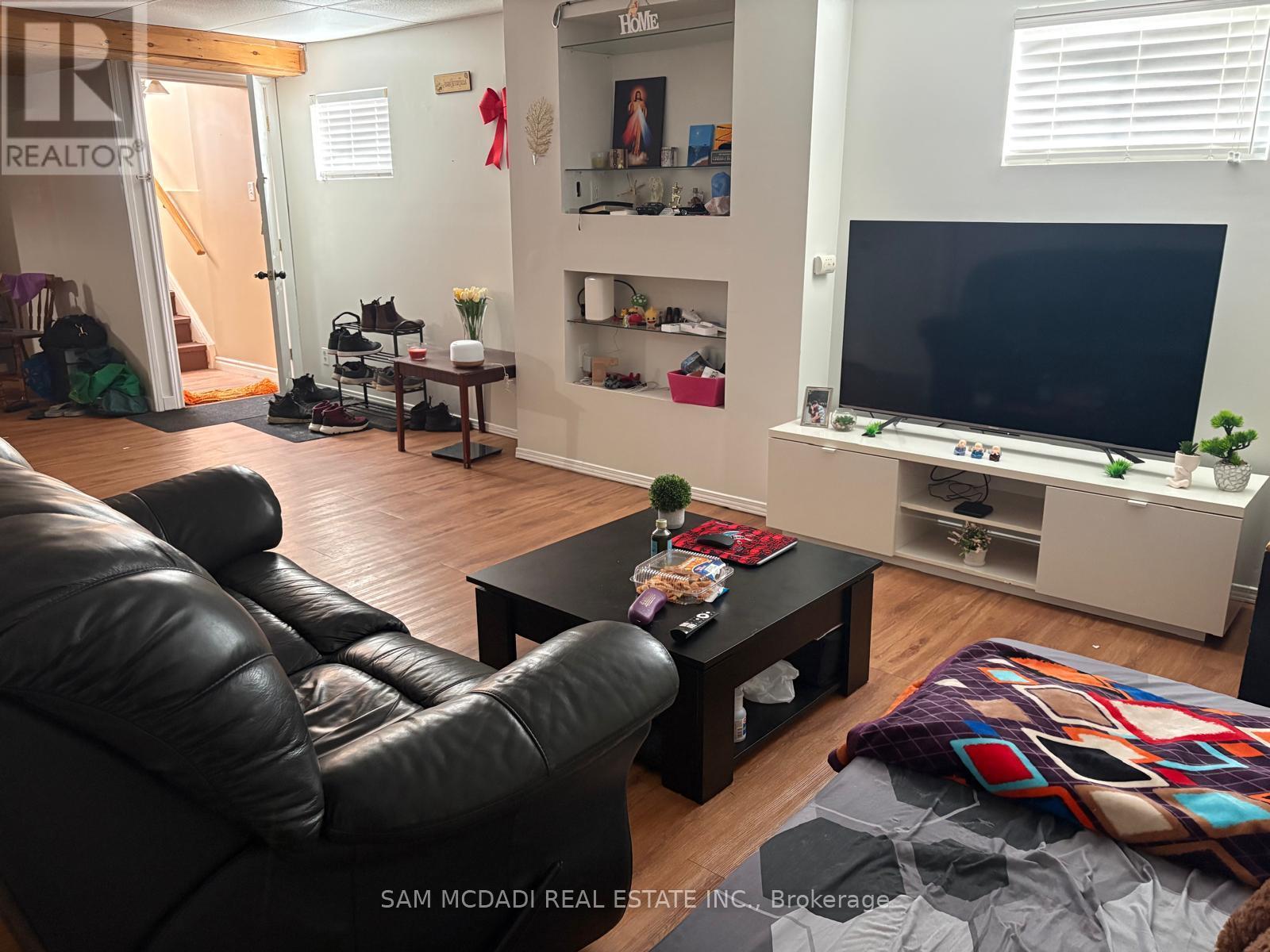 A living room with a black leather couch and a flat screen TV.