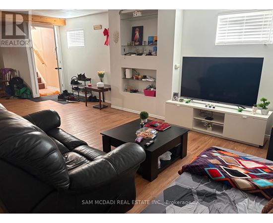 A living room with a black leather couch and a flat screen TV.