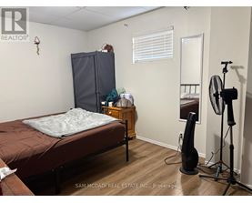 A bedroom with a bed, a wardrobe, a dresser, and a fan.