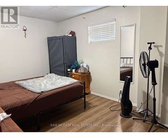 A bedroom with a bed, a wardrobe, a dresser, and a fan.