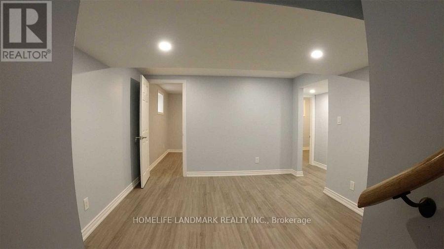 A room with a wooden floor and white walls, with a staircase on the right side.