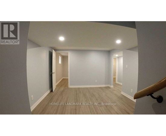 A room with a wooden floor and white walls, with a staircase on the right side.