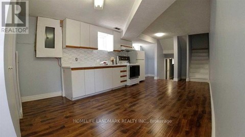 A kitchen with white cabinets and a wooden floor.