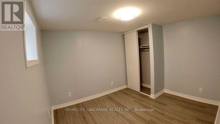 A room with a wooden floor and a white wall with a doorway leading to another room.