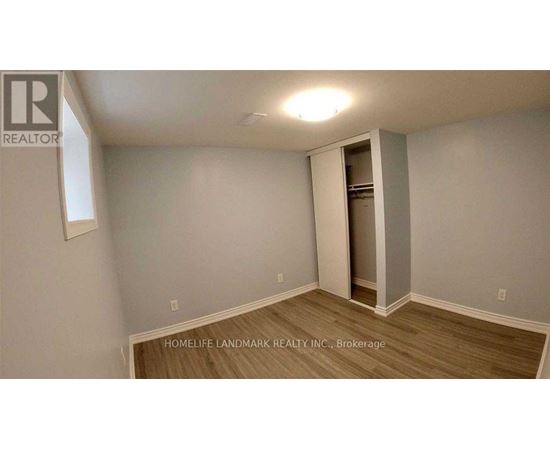 A room with a wooden floor and a white wall with a doorway leading to another room.