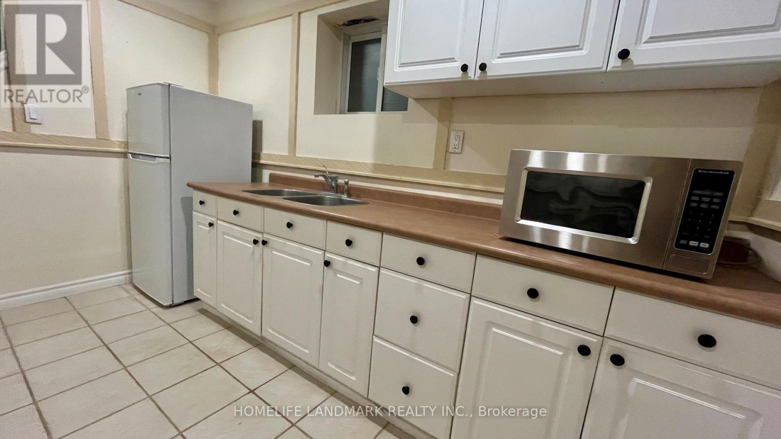 A kitchen with white cabinets and a stainless steel microwave.