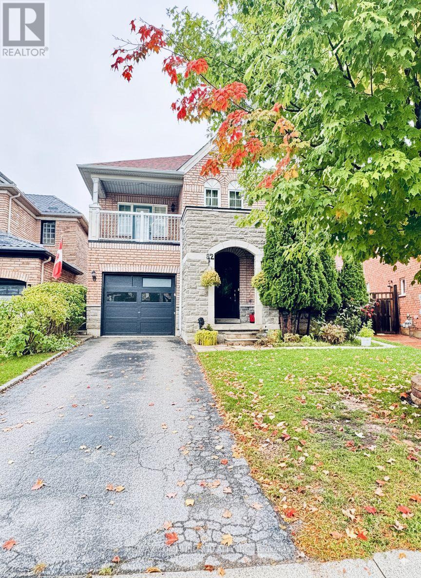 A house with a driveway and a tree with red leaves.