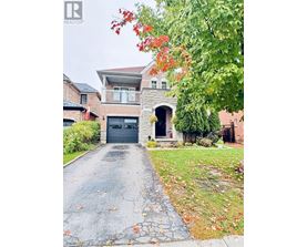 A house with a driveway and a tree with red leaves.