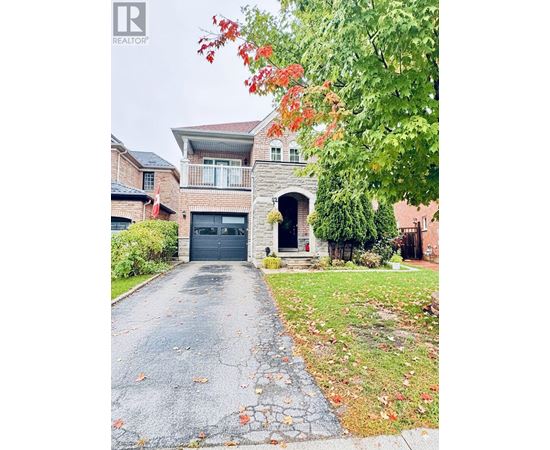 A house with a driveway and a tree with red leaves.