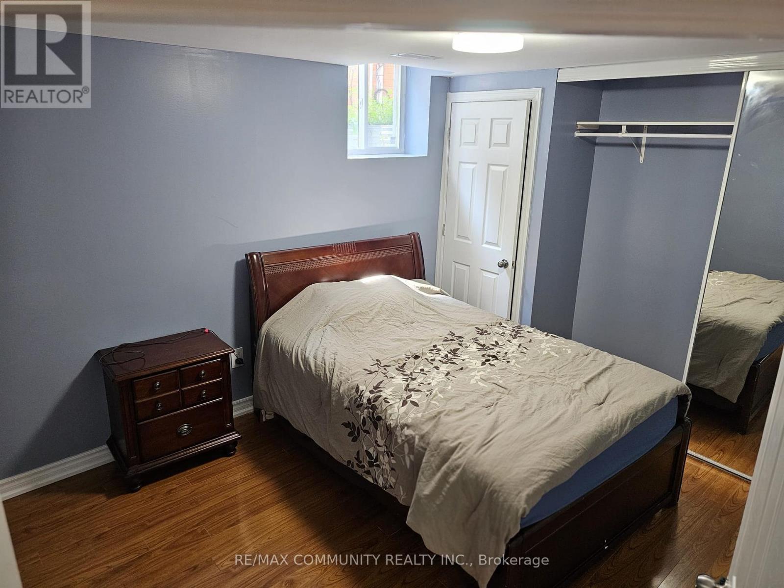 A bedroom with a bed, nightstand, and closet.