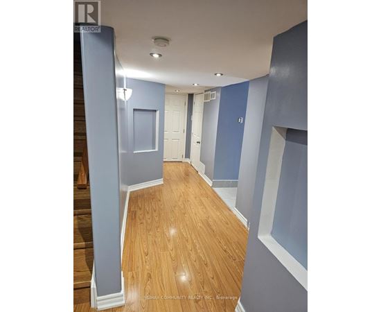 A hallway with wood flooring and blue walls.