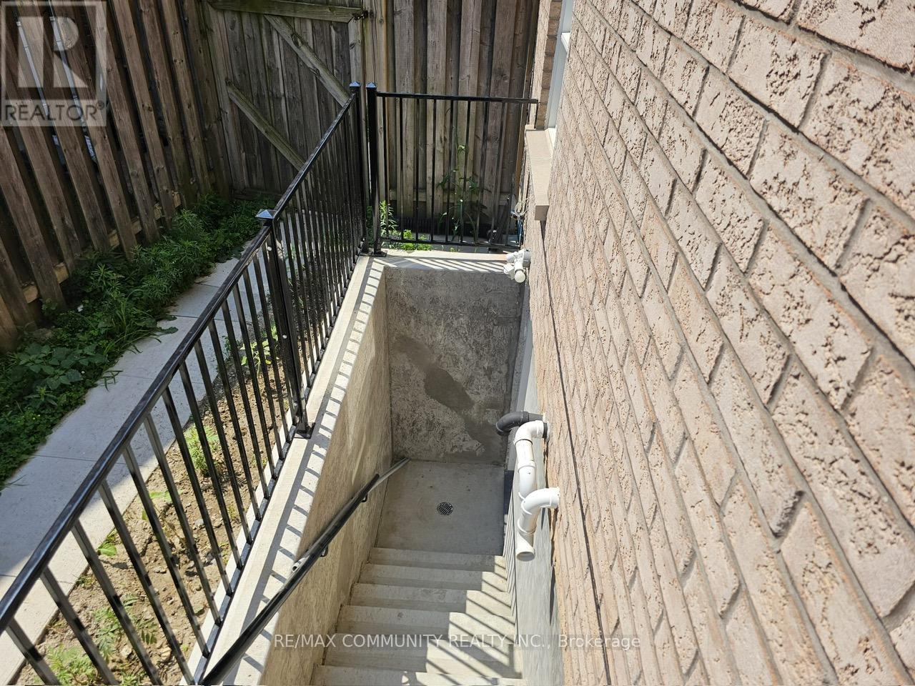 A stairway with a metal railing leads down to a concrete basement.