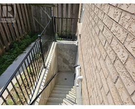 A stairway with a metal railing leads down to a concrete basement.