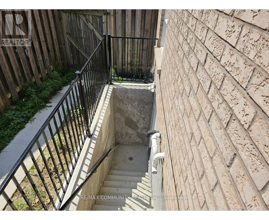 A stairway with a metal railing leads down to a concrete basement.