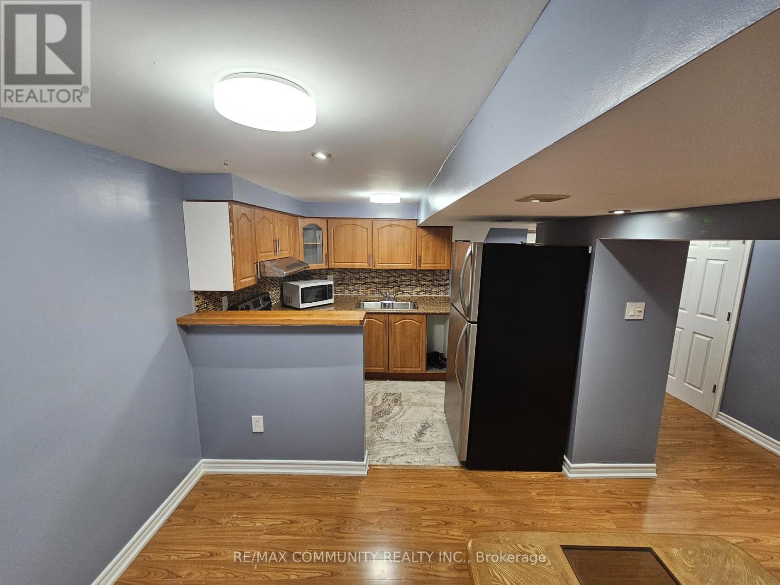 A kitchen with a black refrigerator and wooden cabinets.