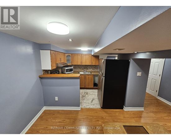 A kitchen with a black refrigerator and wooden cabinets.