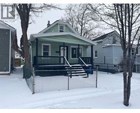 A green house with a black fence in the snow.