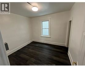 A room with a window and wooden flooring.