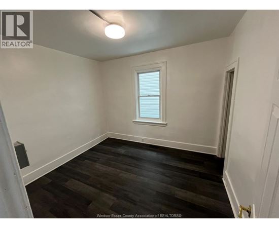 A room with a window and wooden flooring.