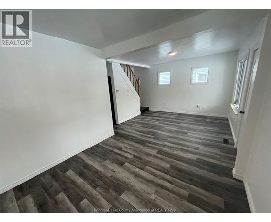 A room with wooden flooring and white walls.