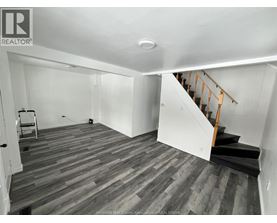 A room with wooden flooring and a staircase.