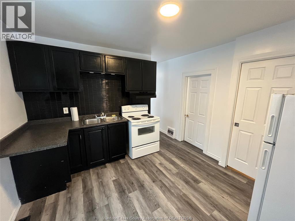 A kitchen with black cabinets and a white stove top oven.
