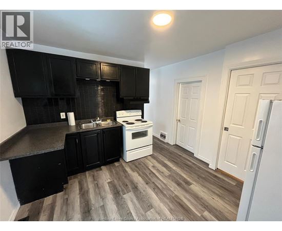 A kitchen with black cabinets and a white stove top oven.